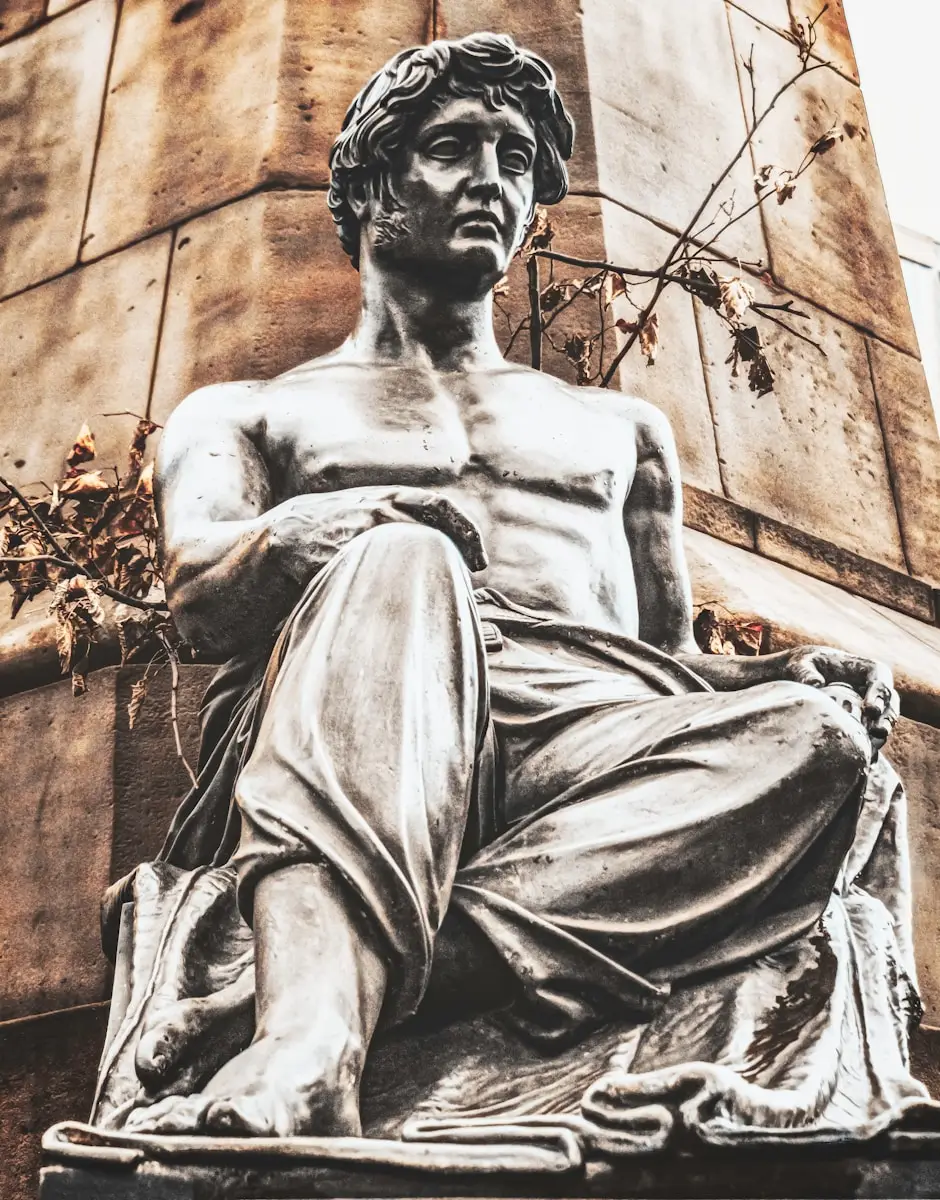 a statue of a man sitting in front of a tall building